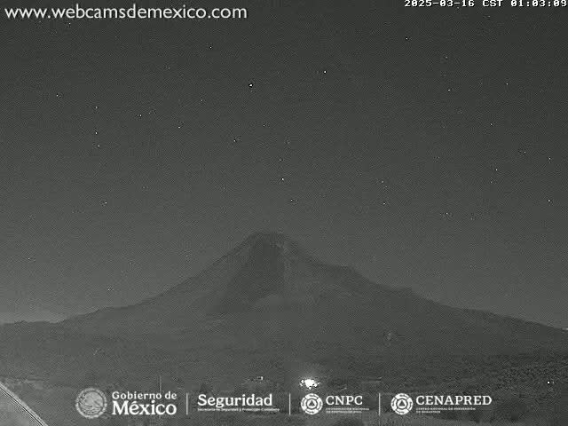 A dark, starlit night reveals a large, silhouetted mountain in the distance.