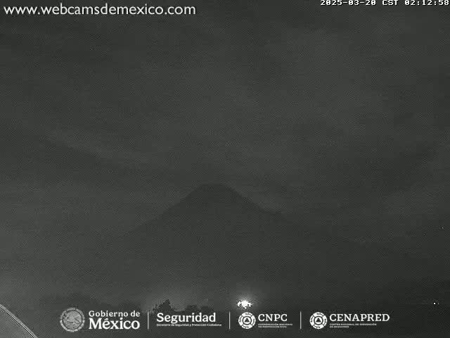 A dark, nighttime image shows a low-lying mountain shrouded in a hazy atmosphere.