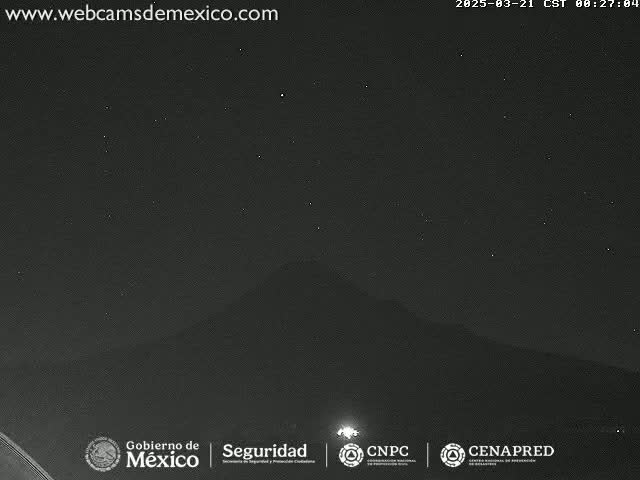 A nighttime long shot of a dark mountain range under a clear, starry sky.