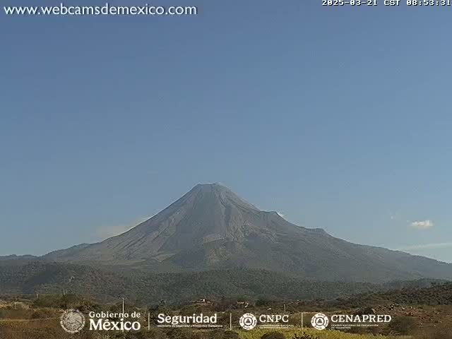A large, dark-colored volcano is visible under a clear, light-blue sky.