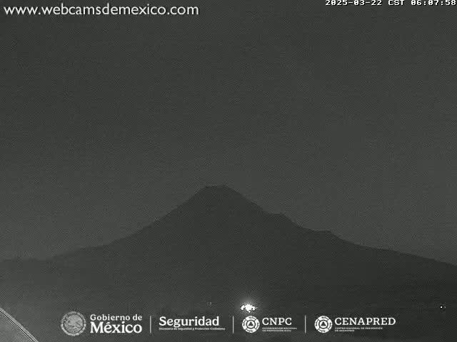 A dark, nighttime view shows a large, silhouetted mountain under a clear sky.