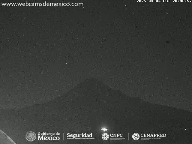 A nighttime, clear-sky view shows a dark, large mountain silhouetted against a starlit sky.