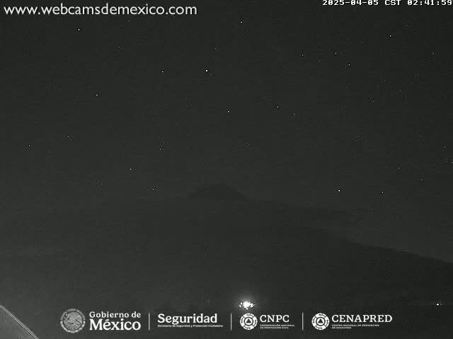 A nighttime long shot of a dark, starlit sky above a mountain range under clear conditions.