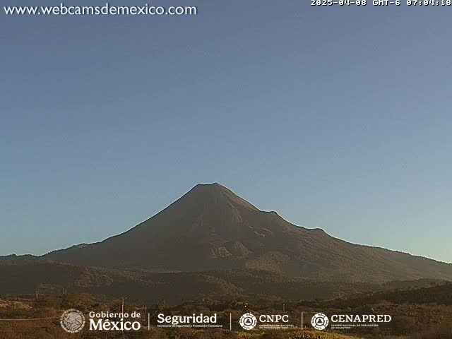 A large, dark-colored volcano is visible against a clear, light-blue sky.