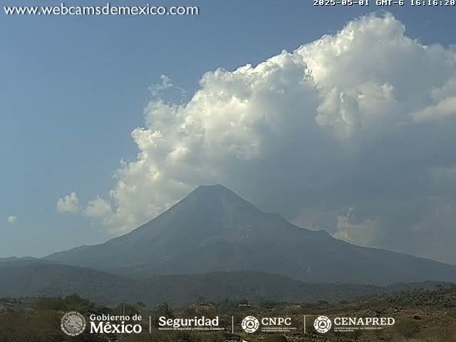 A large, dark volcano is visible beneath a partly cloudy sky.