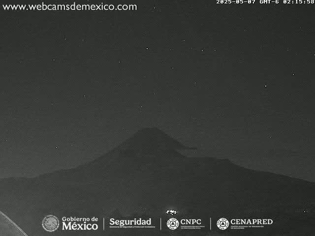 A dark, nighttime view of a large, silhouetted mountain under a clear, starry sky.