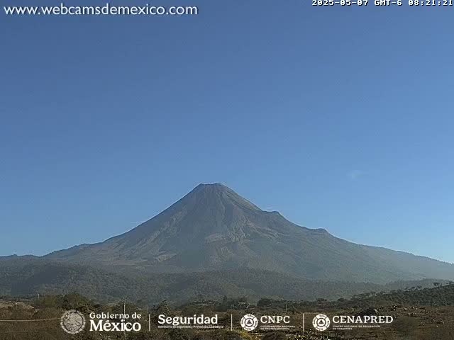A large, dark-colored volcano is visible under a clear, light-blue sky.