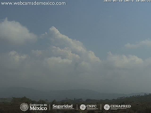 A hazy, partly cloudy sky overlooks a distant line of dark green hills.