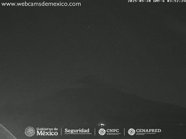 A nighttime, dark gray image shows a mostly clear sky with a few faint lights visible in the distance.