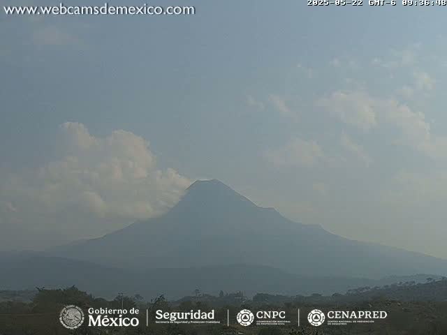 A hazy, partly cloudy day reveals a large, dark mountain range in the distance.