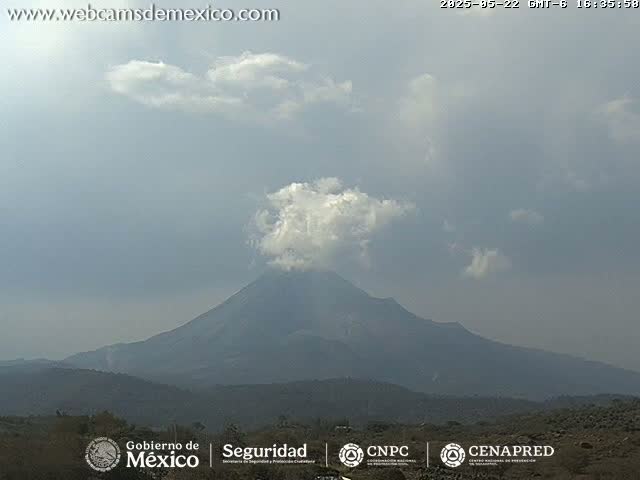 A large, dark volcano is visible under a mostly cloudy, light gray sky.