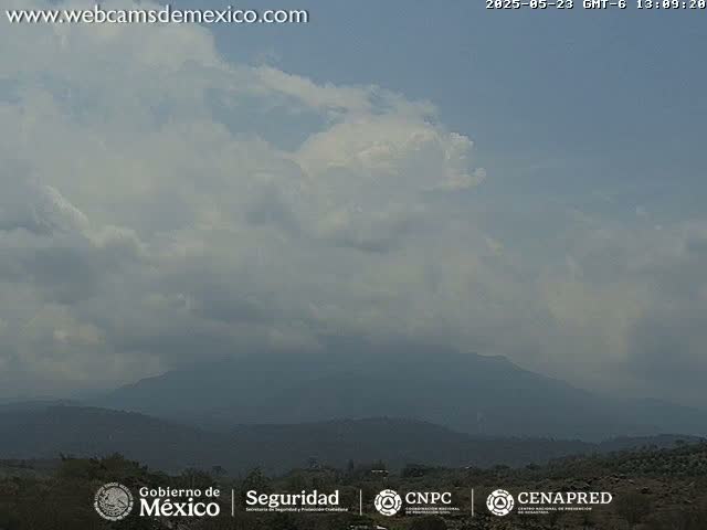 A partly cloudy sky overlooks a hazy mountain range.
