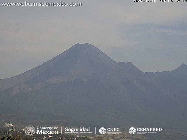 A large, hazy mountain range is visible under a cloudy sky.