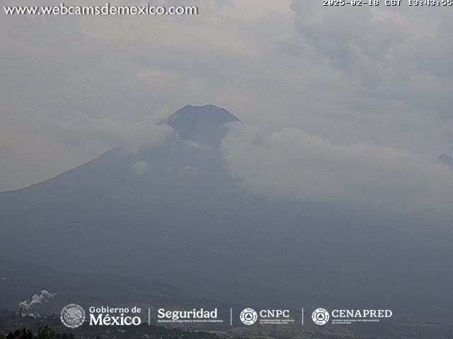 A large, partially cloud-covered mountain is seen on an overcast day.
