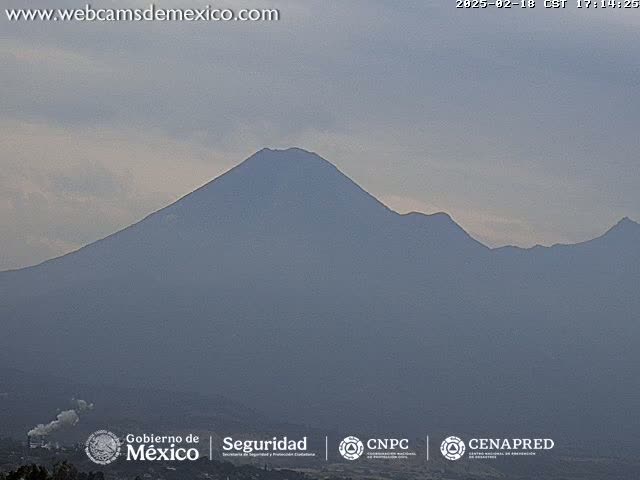 A large, hazy mountain range is visible under a cloudy sky.