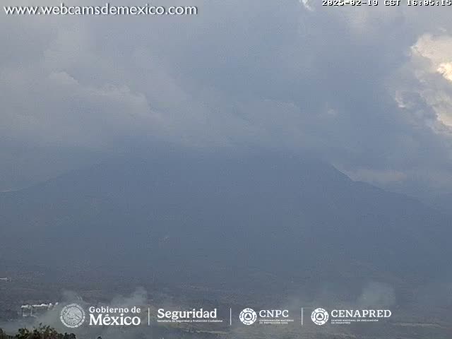 A hazy, overcast day reveals a distant mountain range with a hint of smoke or fog near the base.