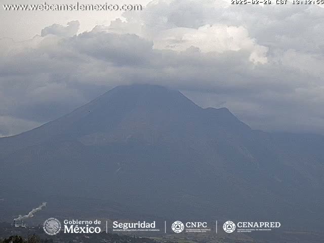 A large, dark-colored mountain is visible under a mostly cloudy sky.