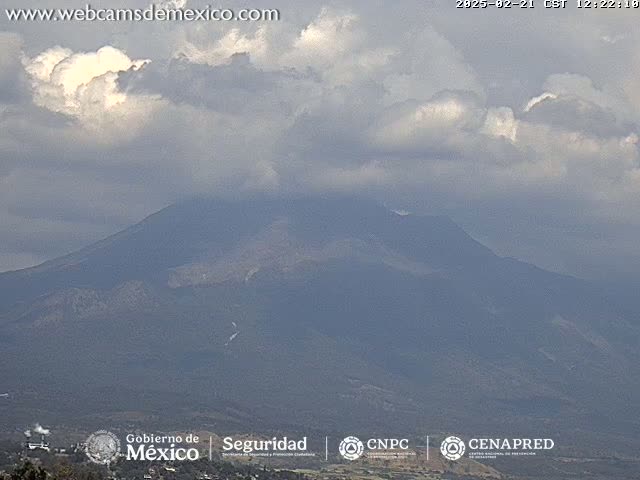 A large, dark mountain is partially obscured by a cloudy sky.