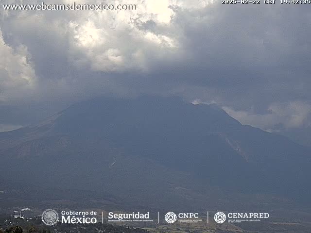 A large, dark mountain is partially obscured by a cloudy sky.