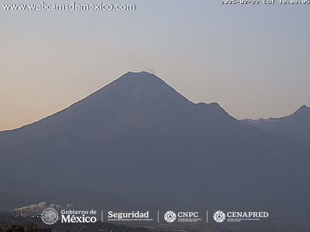 A large, dark-colored mountain is visible under a pale, dusky sky.