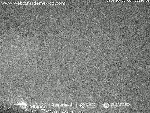 A low-light, grainy image shows a dark, overcast sky over a landmass at night.
