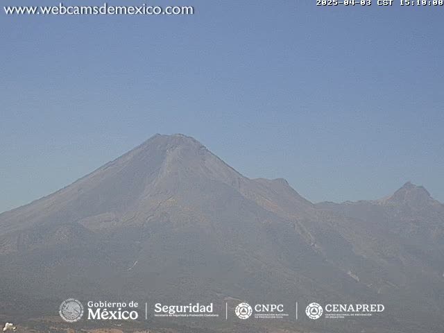 A hazy view of a large, dark-colored mountain range under a clear blue sky.