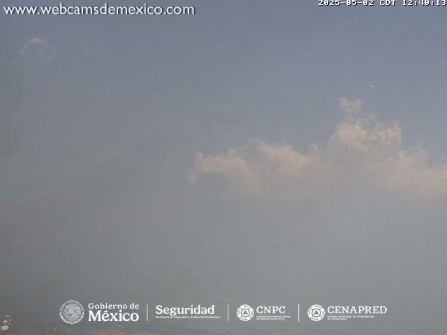 A hazy, mostly clear sky with a few wispy clouds is visible.