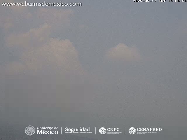 A hazy, overcast sky shows a few small, fluffy clouds.