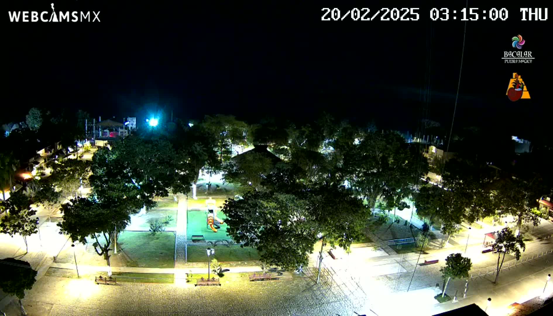 A nighttime aerial view of a park with illuminated walkways and trees, under a clear, dark sky.