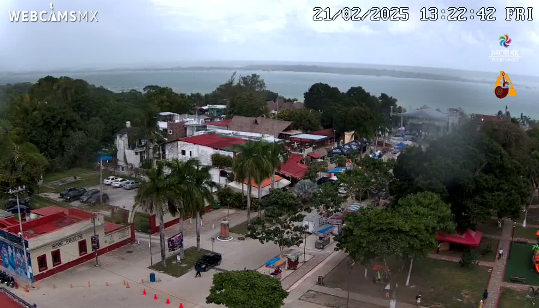 An aerial view of a town square and surrounding buildings near a body of water under an overcast sky.