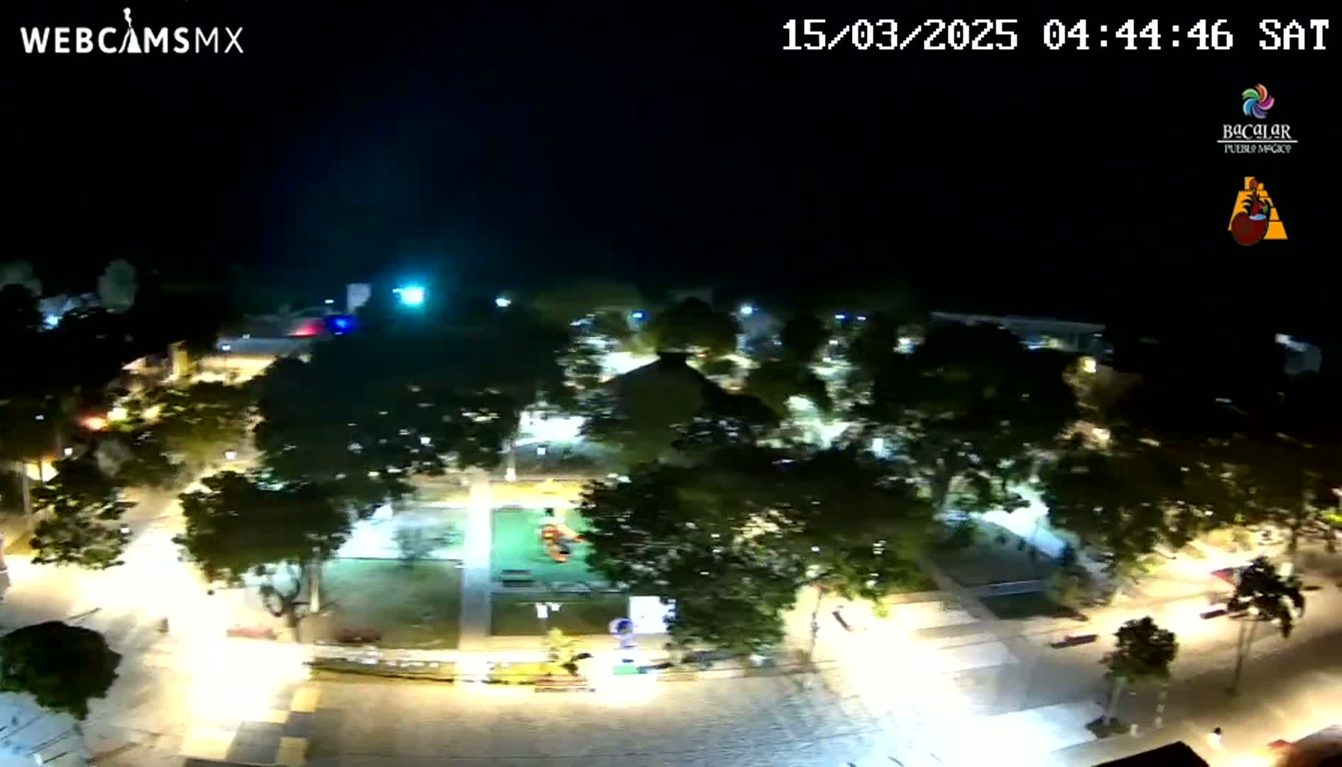A nighttime aerial view of a park and surrounding streets, illuminated by artificial lights.