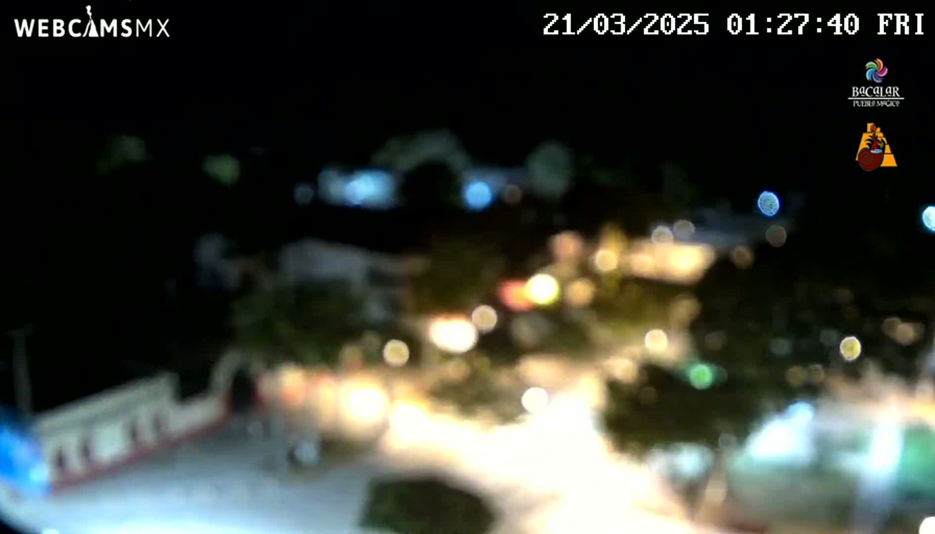 A blurry nighttime aerial view of a town with numerous out-of-focus lights.