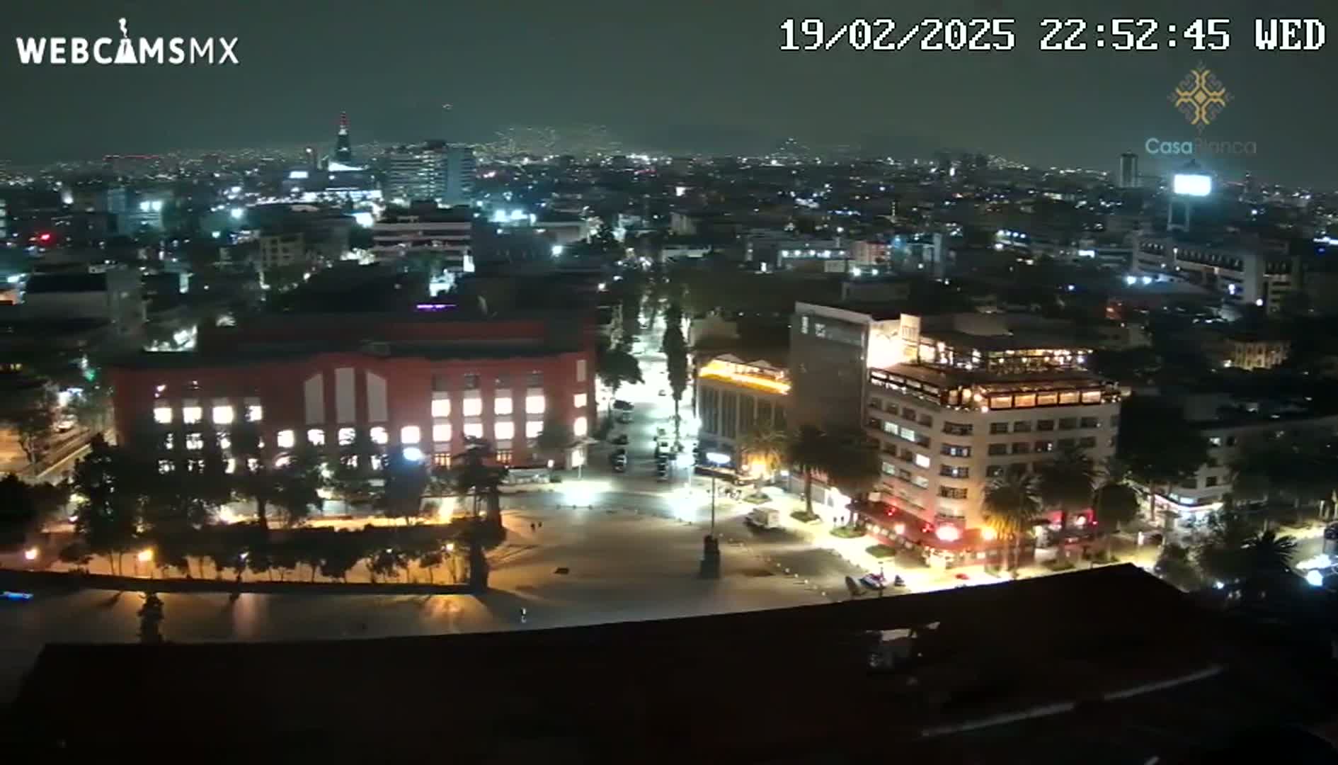 A nighttime aerial view of a city illuminated by streetlights and building lights under a dark sky.