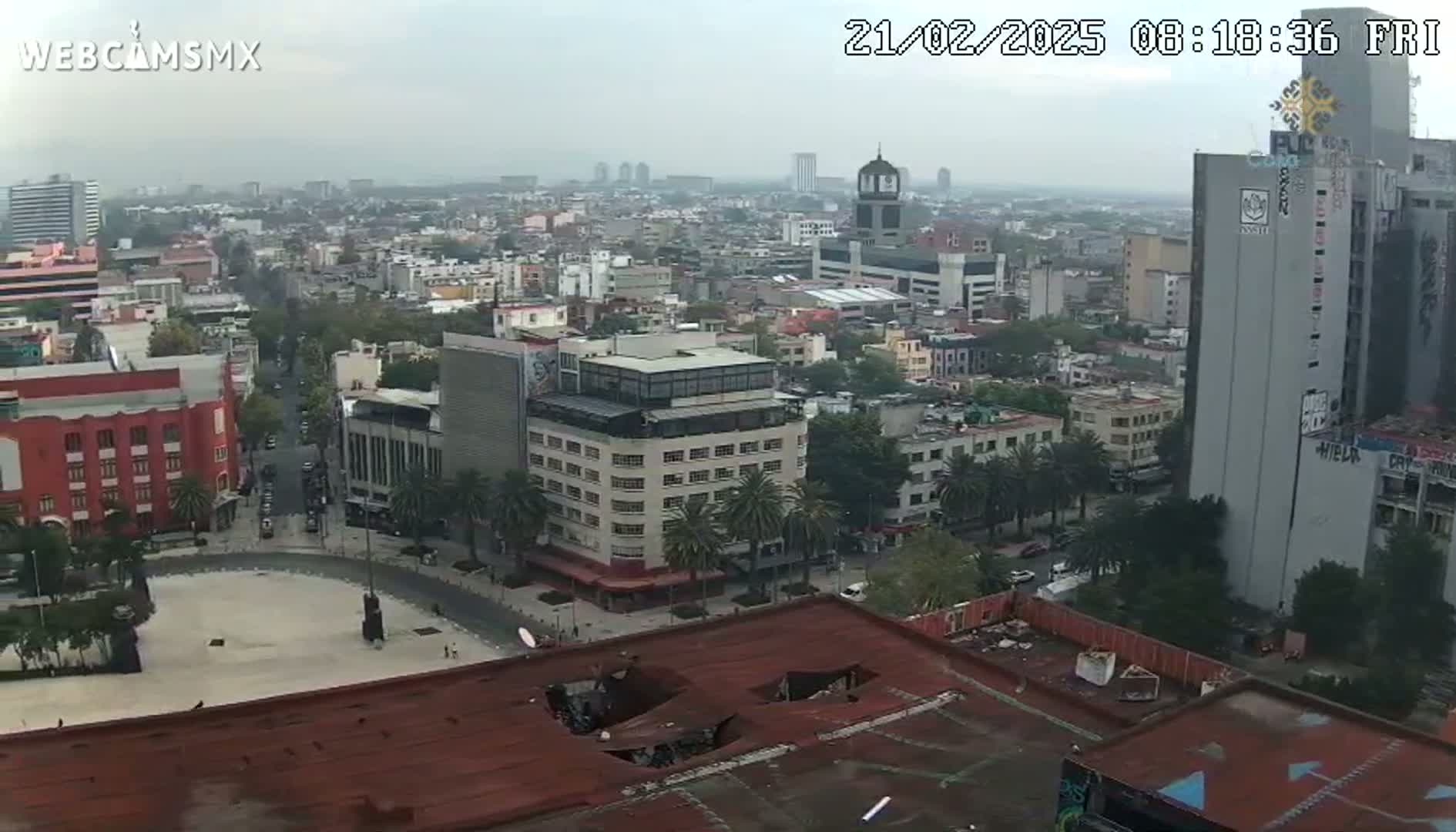 A hazy city view shows a cityscape with many buildings and streets, viewed from a high vantage point on an overcast day.