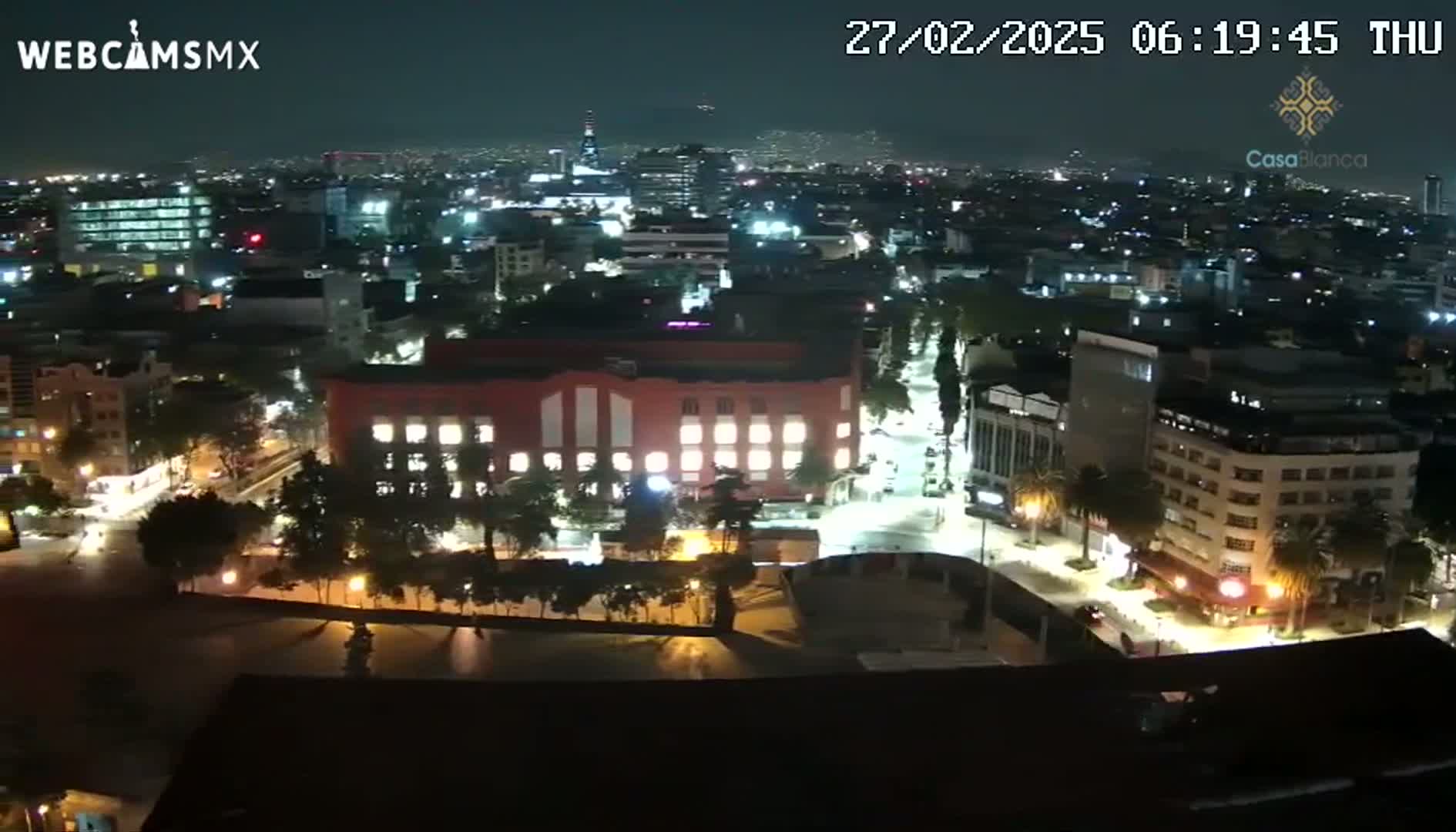 A nighttime aerial view of a city illuminated by streetlights and building lights under a clear sky.