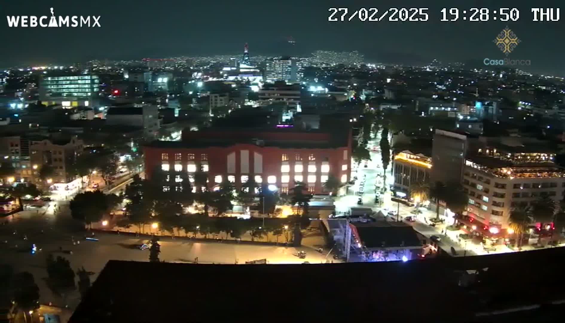 A nighttime aerial view of a city illuminated by streetlights and building lights, under a clear sky.