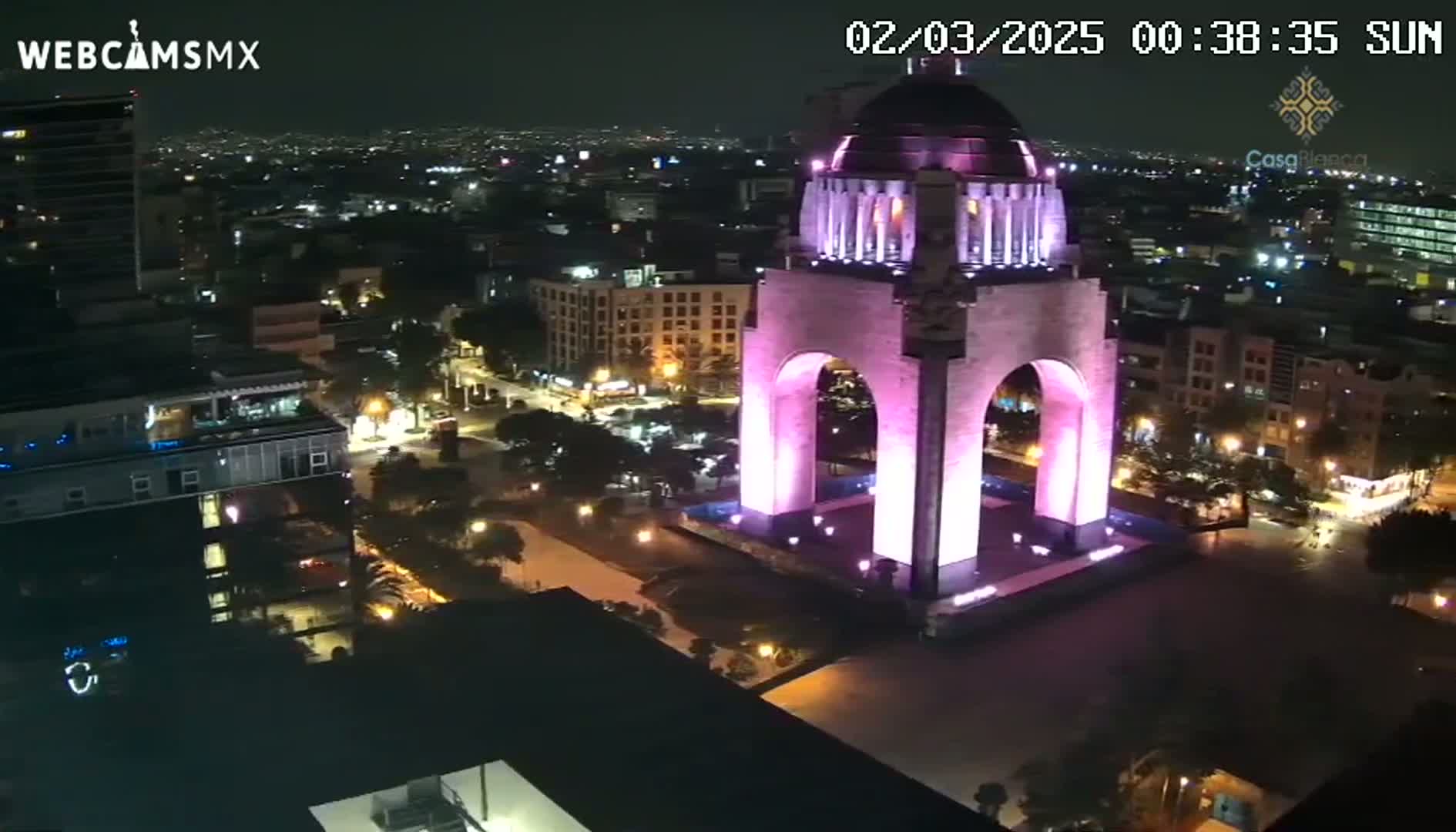 A pink-lit monument stands in a city at night.