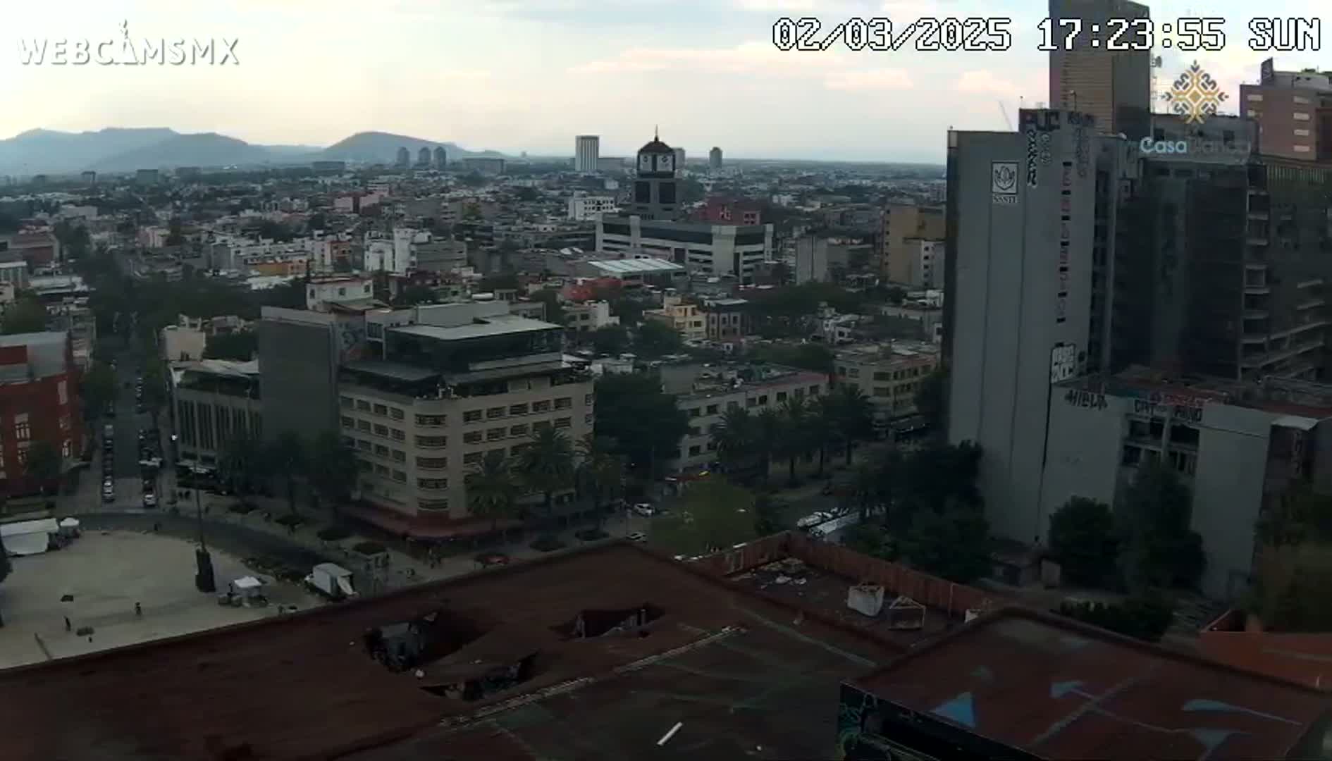 An overcast, high-angle view of a city with numerous buildings, including several high-rises, under a cloudy sky.