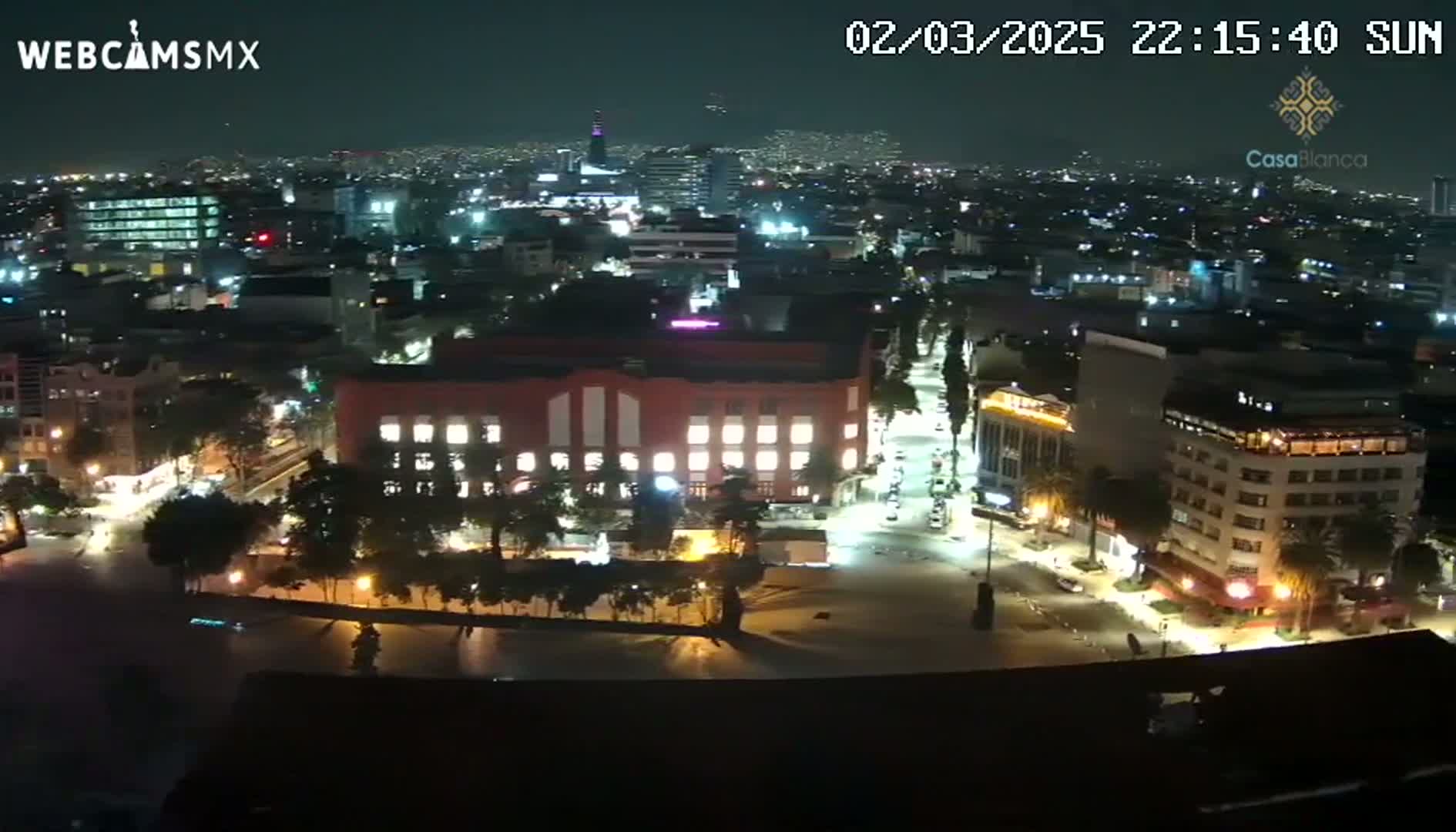 A nighttime aerial view of a city illuminated by streetlights and building lights, under a clear sky.