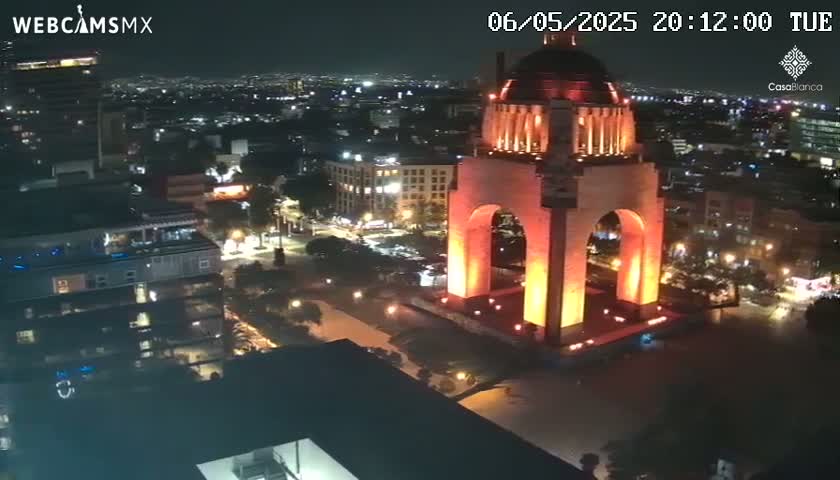 A large, illuminated monument stands in the center of a nighttime cityscape.
