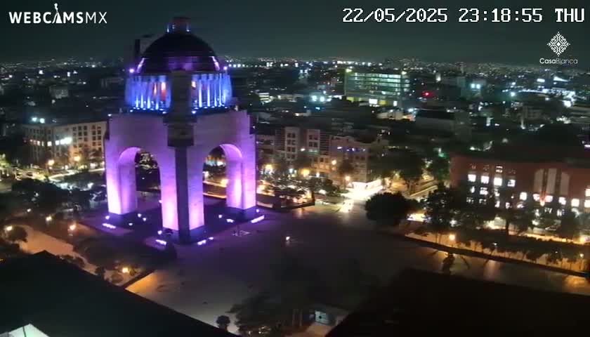 A large, illuminated monument stands in a city at night.