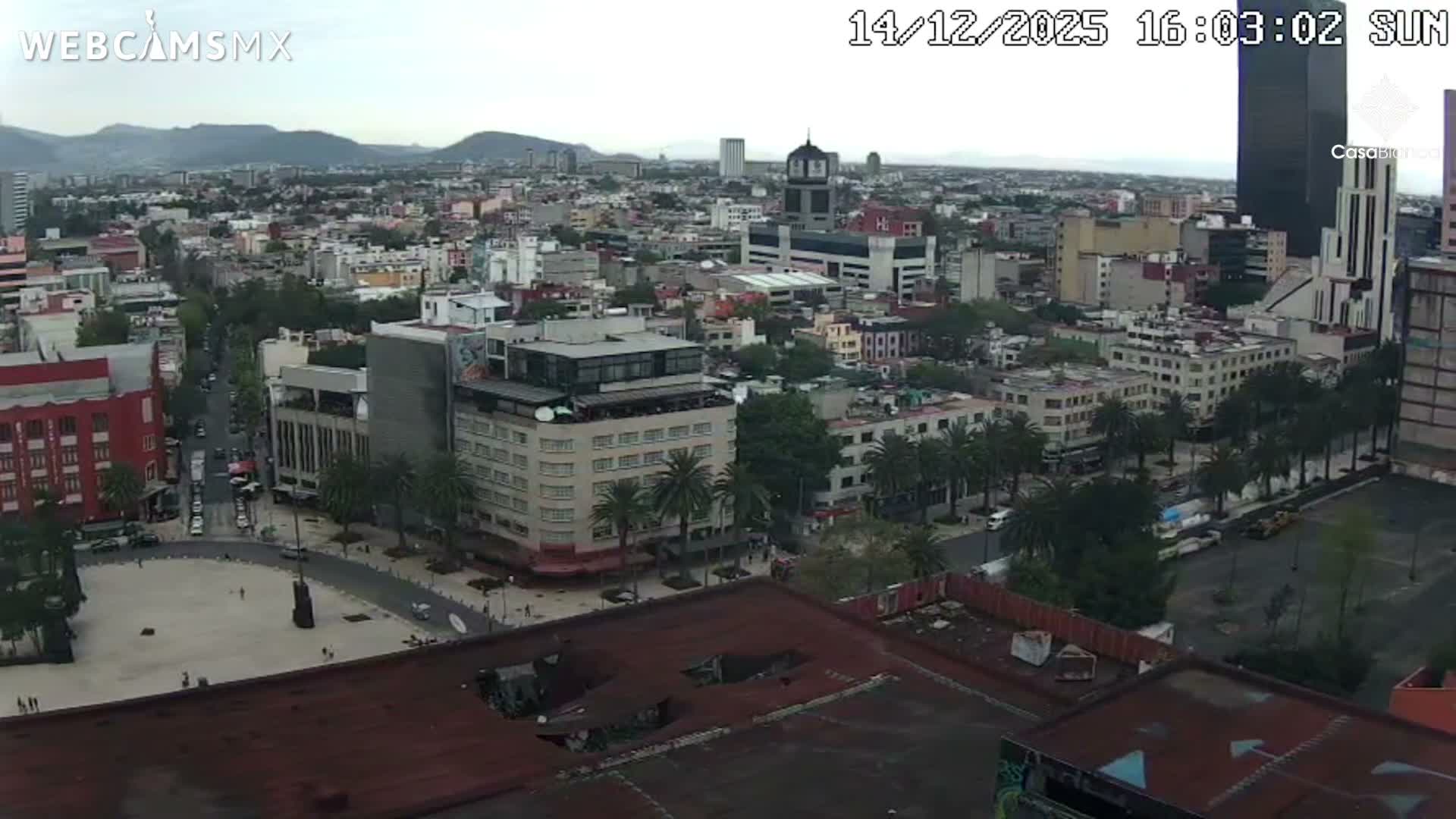 An illuminated monument glowing purple stands prominently in a sprawling city at night under clear skies.