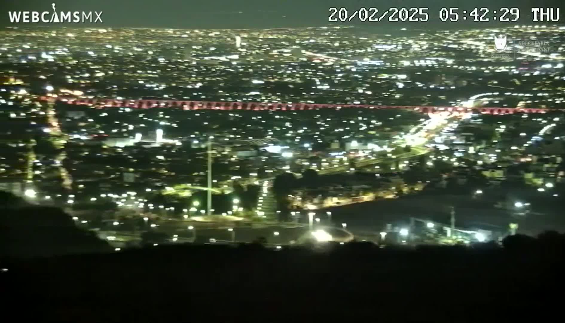 A nighttime, high-angle view of a sprawling city illuminated by countless lights.