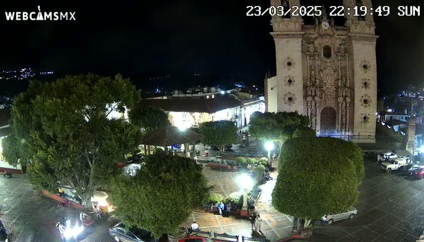 A nighttime view of a town square with a large church in the background, under clear skies.