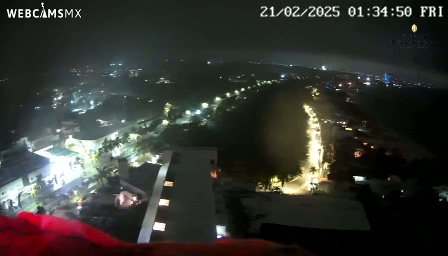 A nighttime, high-angle view shows a city with illuminated streets and buildings, partially obscured by a hazy atmosphere.