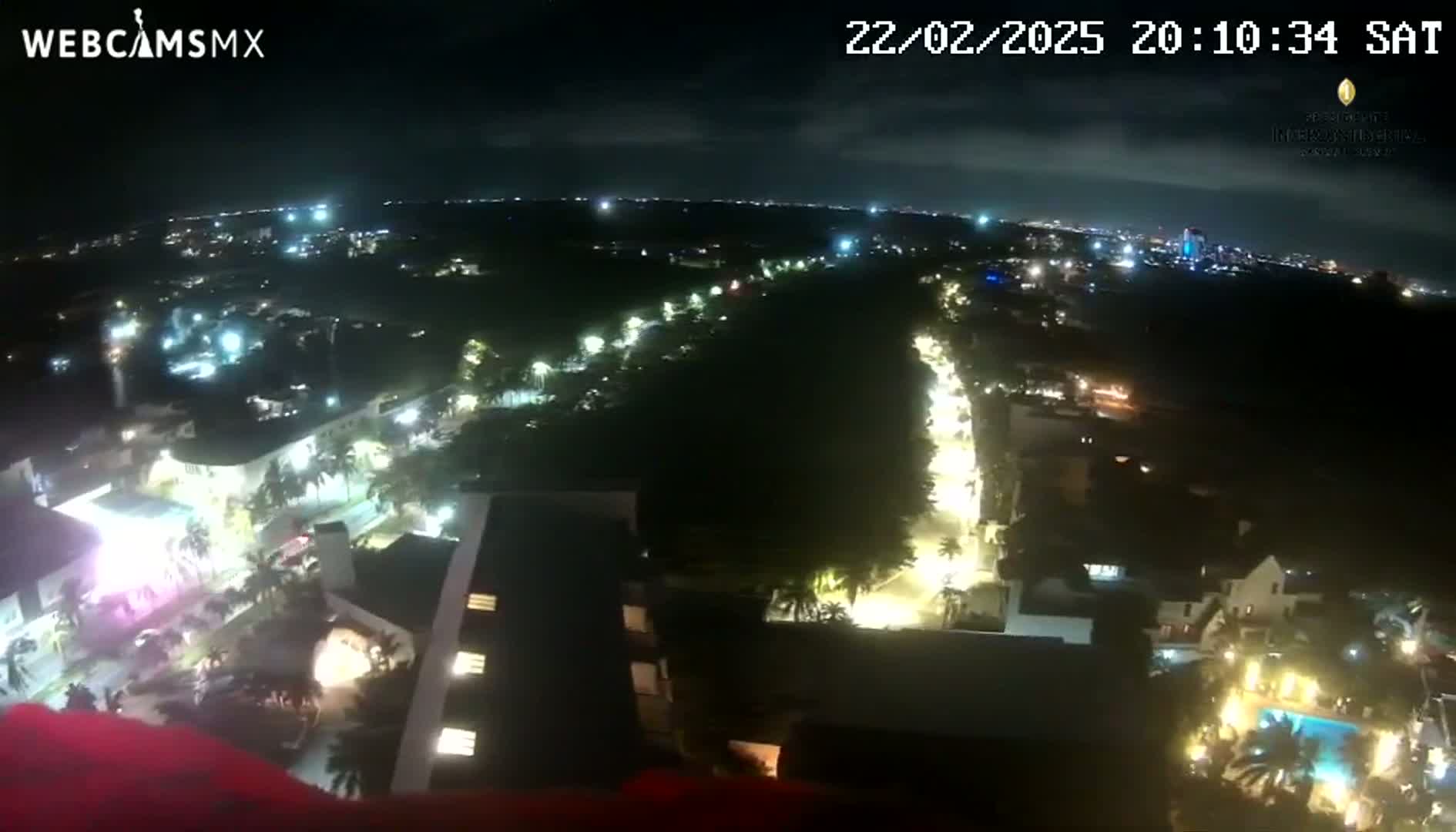 A nighttime aerial view shows a city with illuminated streets and buildings, under a clear sky.