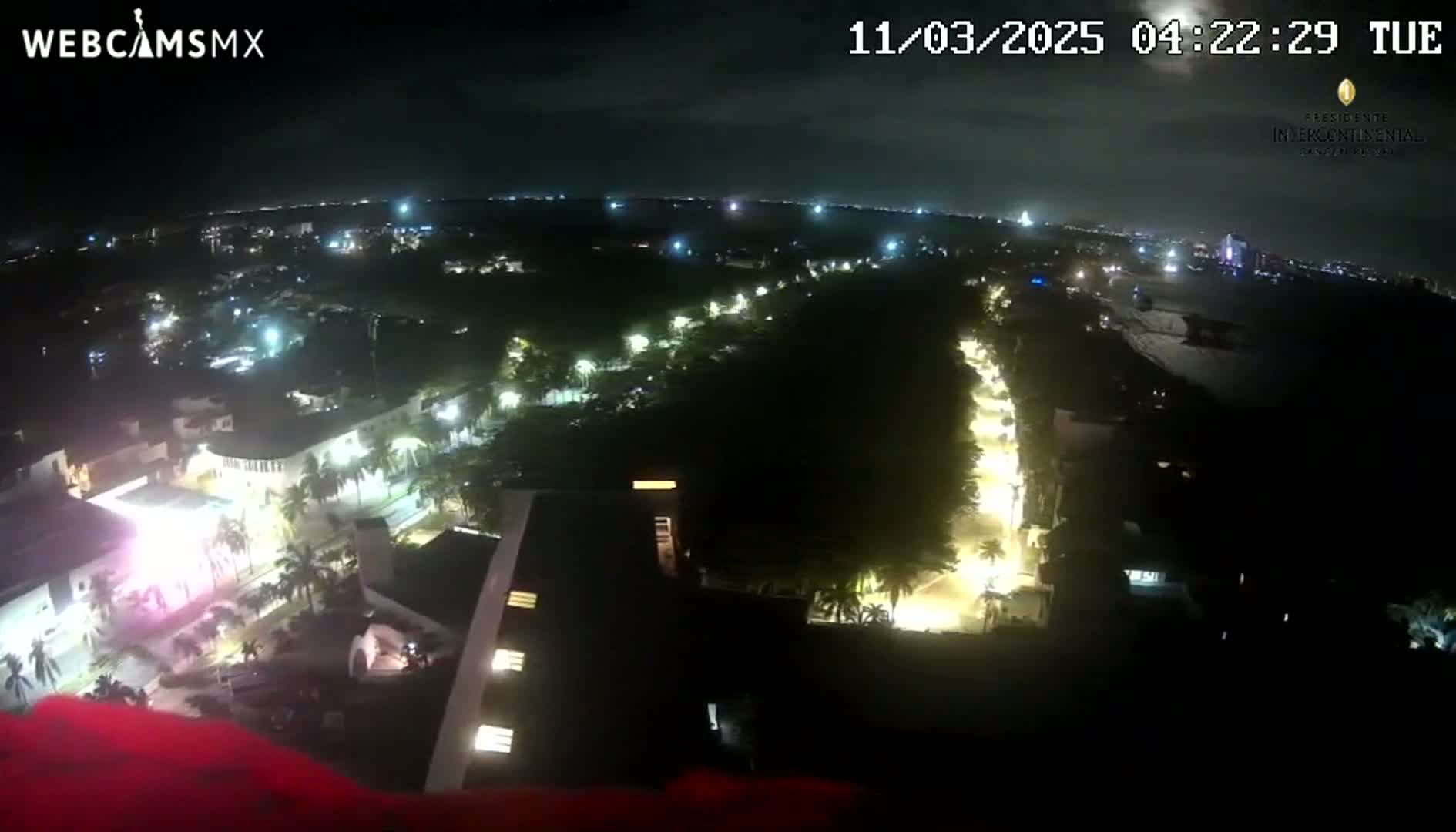 An aerial nighttime view of a city with illuminated streets and buildings under a mostly clear sky.