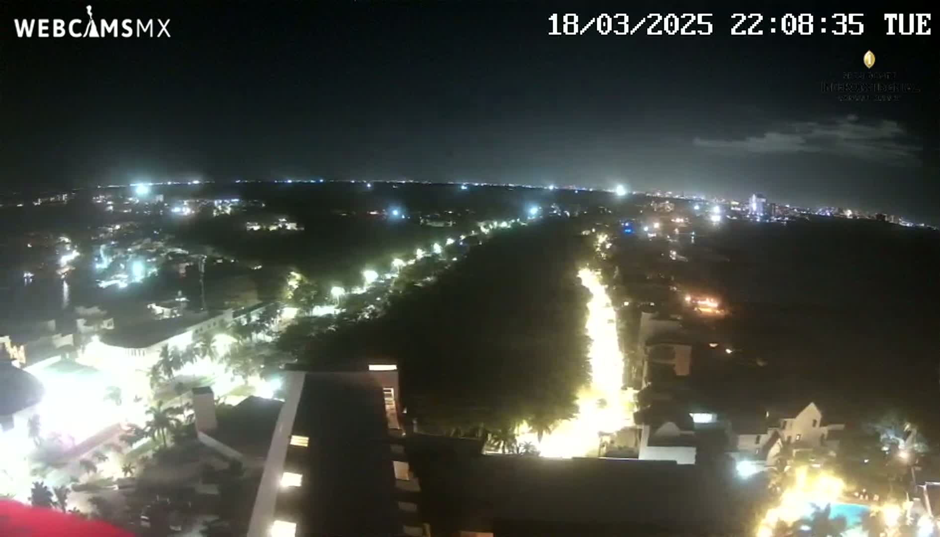 A nighttime, high-angle view shows a city illuminated by streetlights and building lights, with a dark sky overhead.