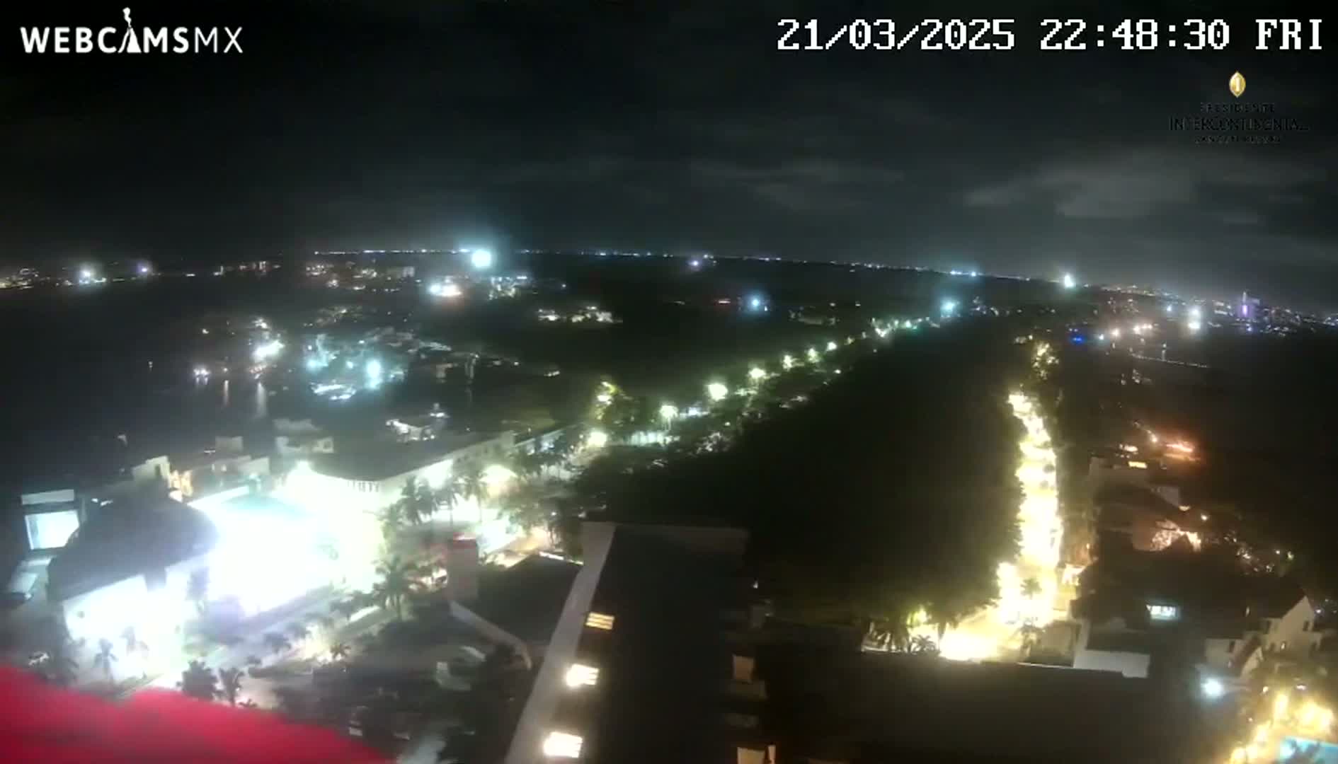 A nighttime aerial view of a city with brightly lit streets and buildings under a mostly clear sky.