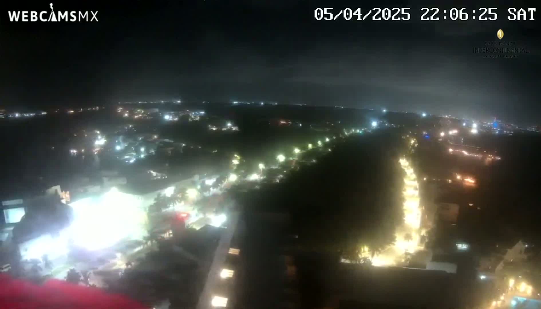 A nighttime aerial view shows a city illuminated with streetlights and building lights under a dark sky.
